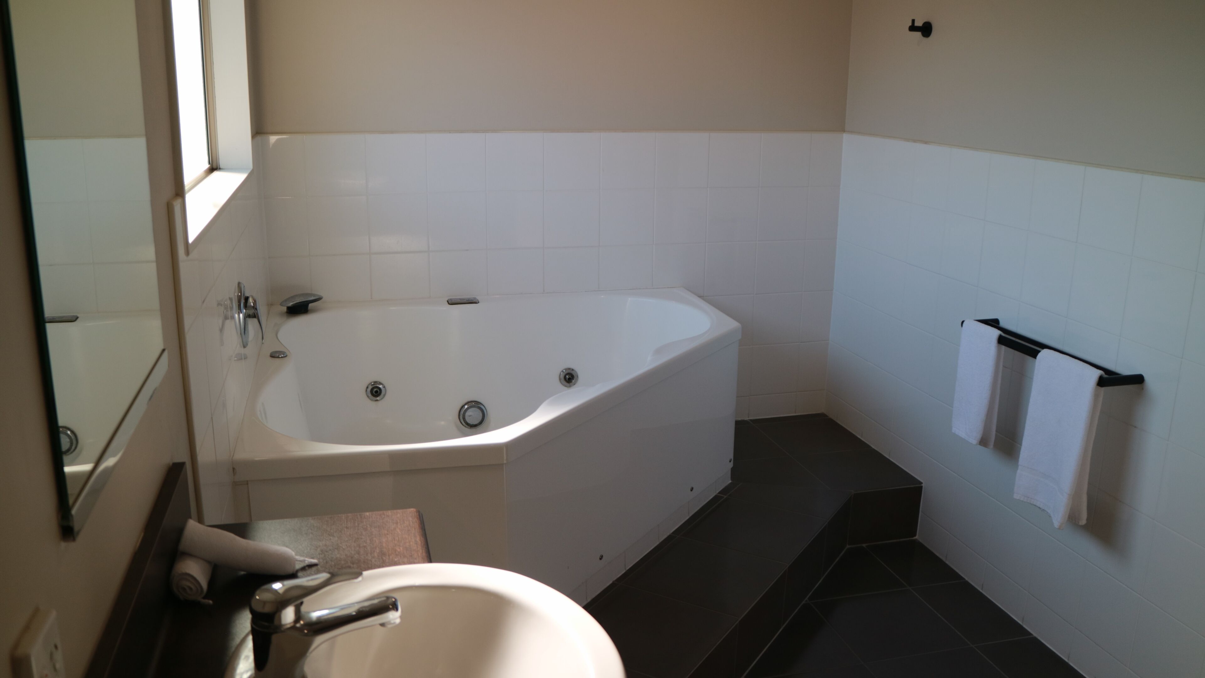 A bathroom with a bathtub, a sink, and a towel rack.