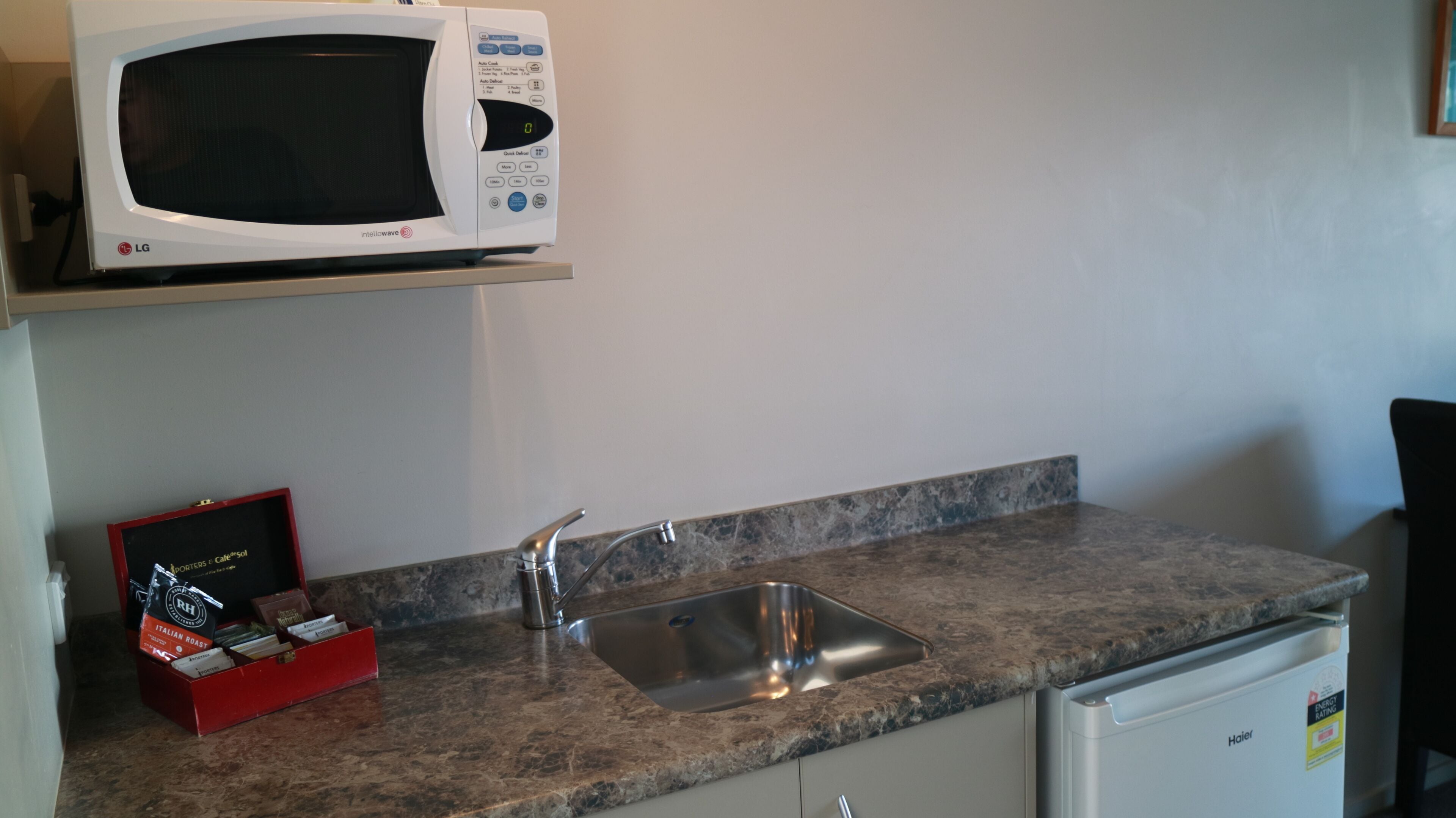 A kitchen with a microwave, sink, and a small refrigerator.