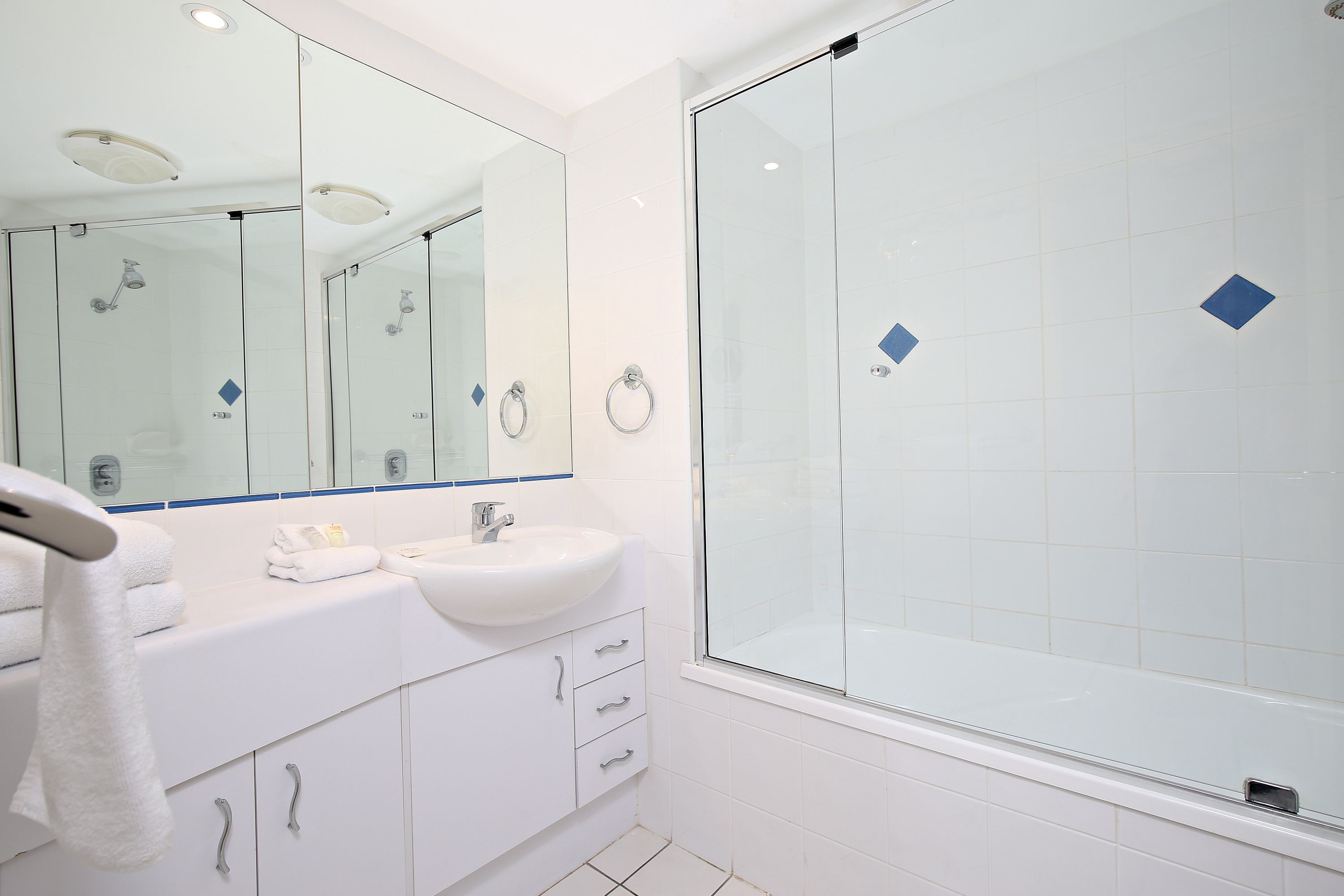 A modern bathroom with a glass-enclosed shower, a white sink, and a large mirror.