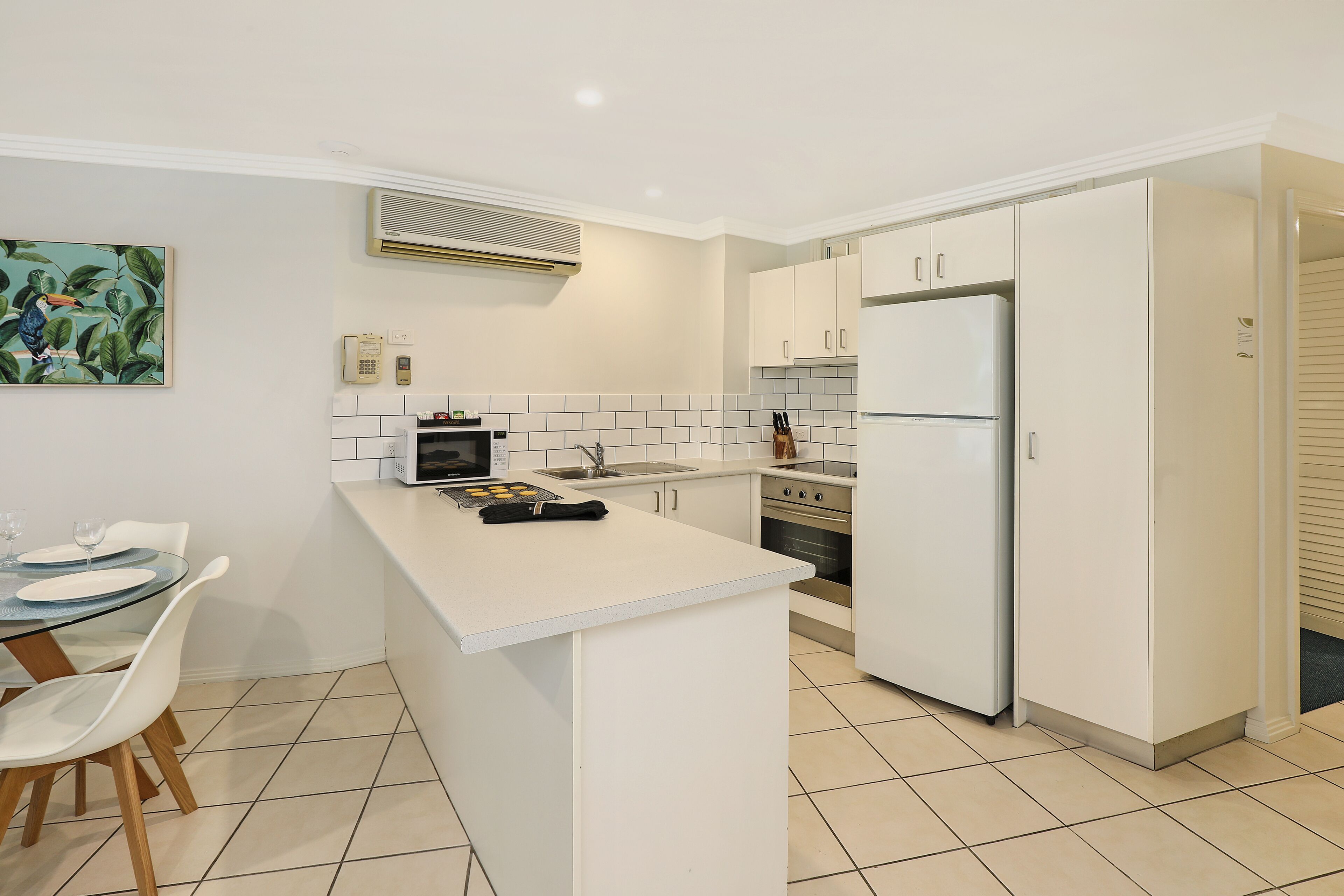 Een moderne keuken met witte kastjes, een centraal eiland, een magnetron en een koelkast.