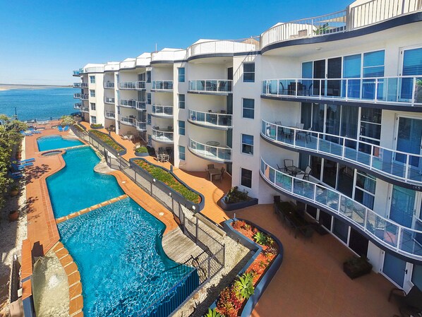 A multi-story hotel with a pool area, outdoor seating, and balconies. - Watermark Resort Caloundra (Caloundra)