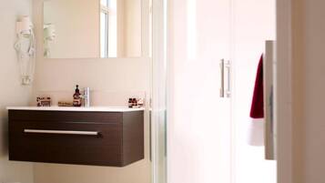 A modern bathroom with a dark wooden vanity, a large mirror, and a glass shower enclosure.