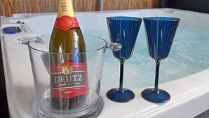 A hot tub with a bottle of Deutz Brut champagne and two blue martini glasses. - Dunedin Palms Motel (Dunedin)