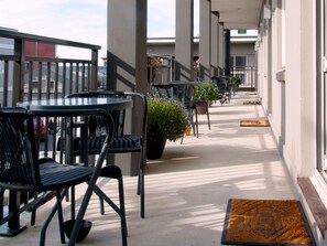 A covered outdoor seating area with tables and chairs, potted plants, and a doormat. - Dunedin Palms Motel (Dunedin)