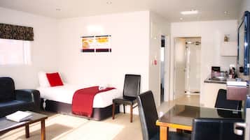 A hotel room with a bed, a desk, a chair, and a coffee table.