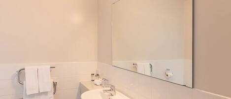 Un baño moderno con lavamanos, espejo y toallero blancos.
