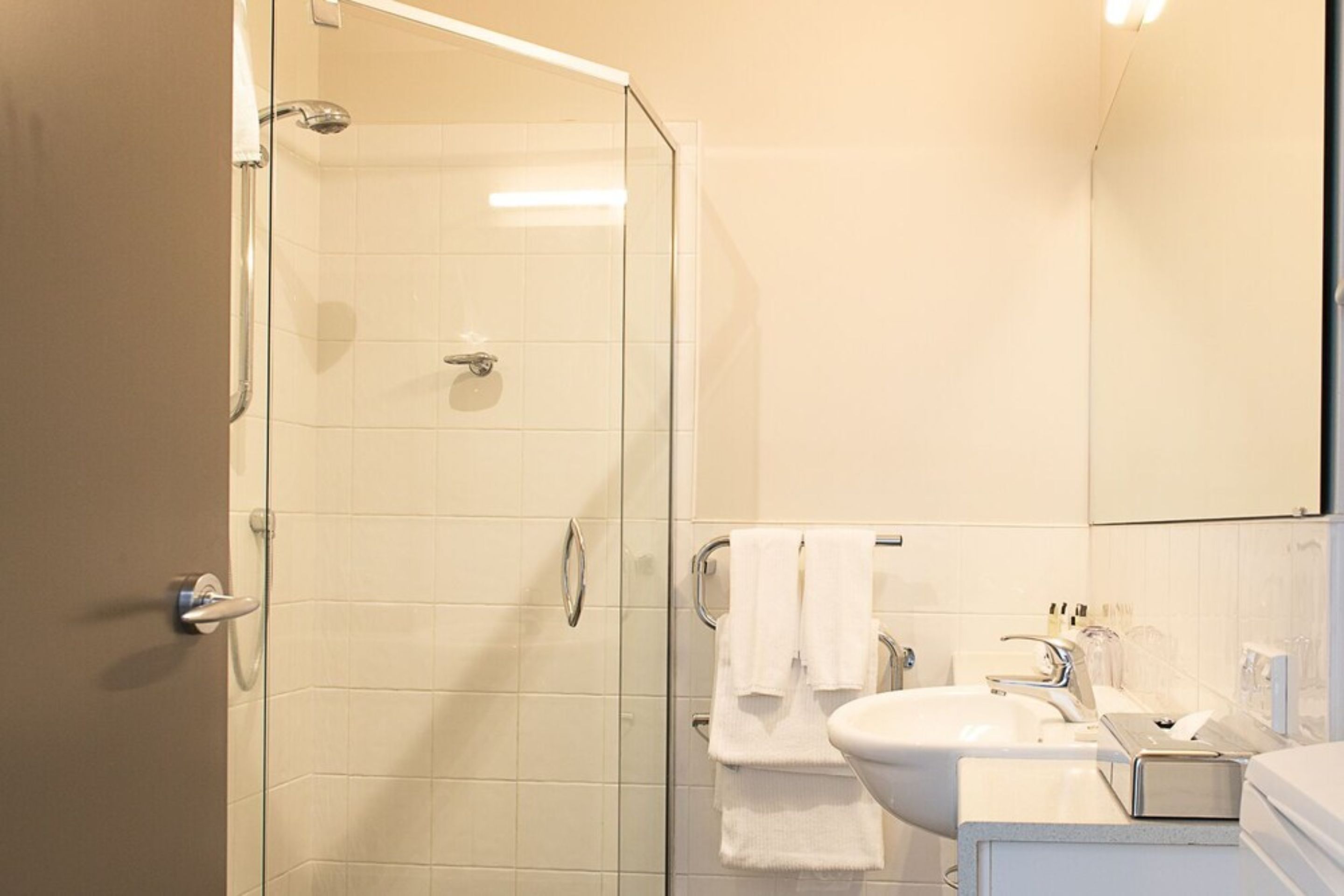 Une salle de bain moderne avec une douche à parois de verre, un lavabo blanc et un miroir.