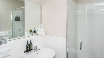 Un bagno moderno con lavandino bianco, specchio e cabina doccia in vetro.