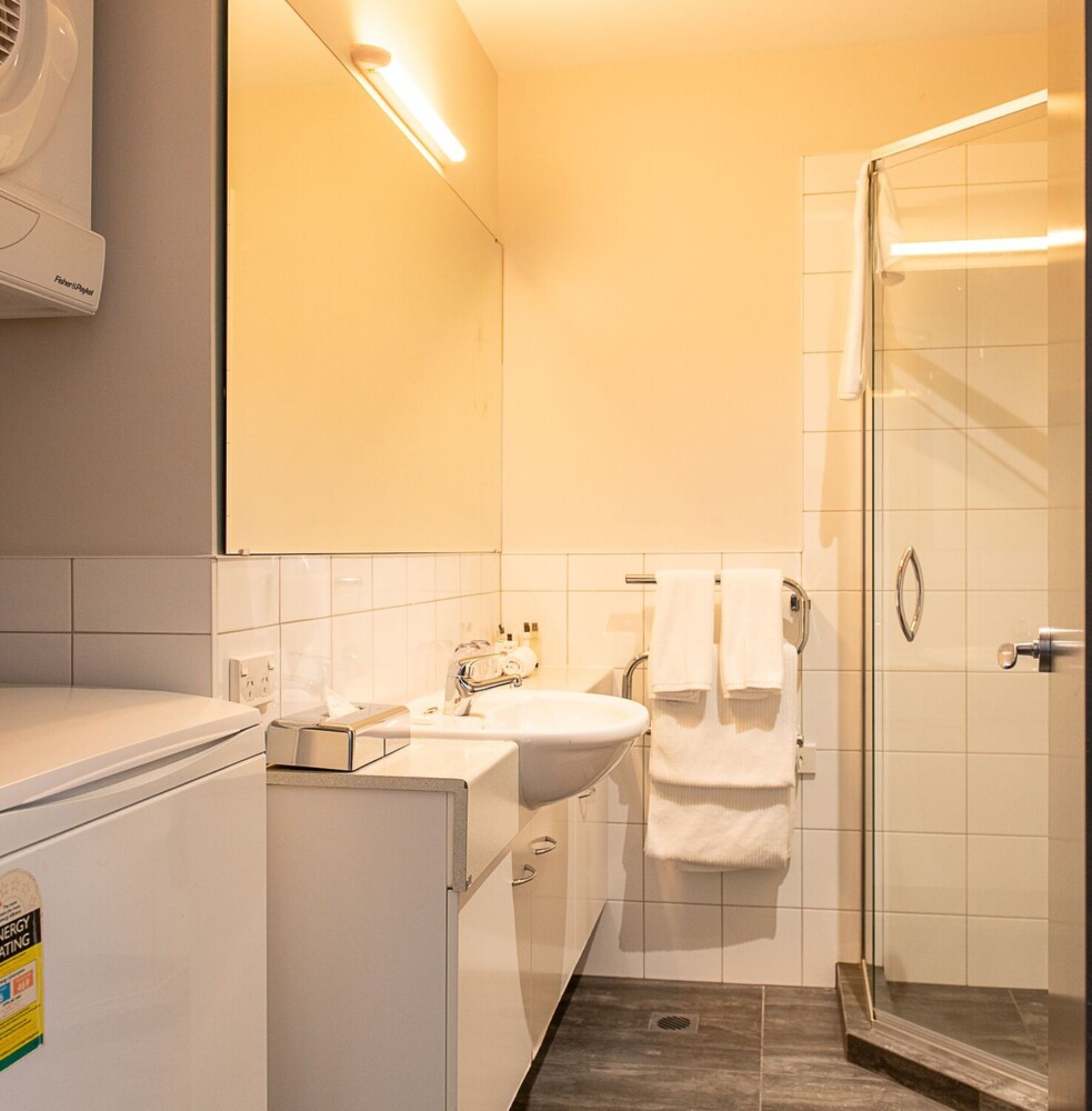 A modern bathroom with a white sink, mirror, and shower.