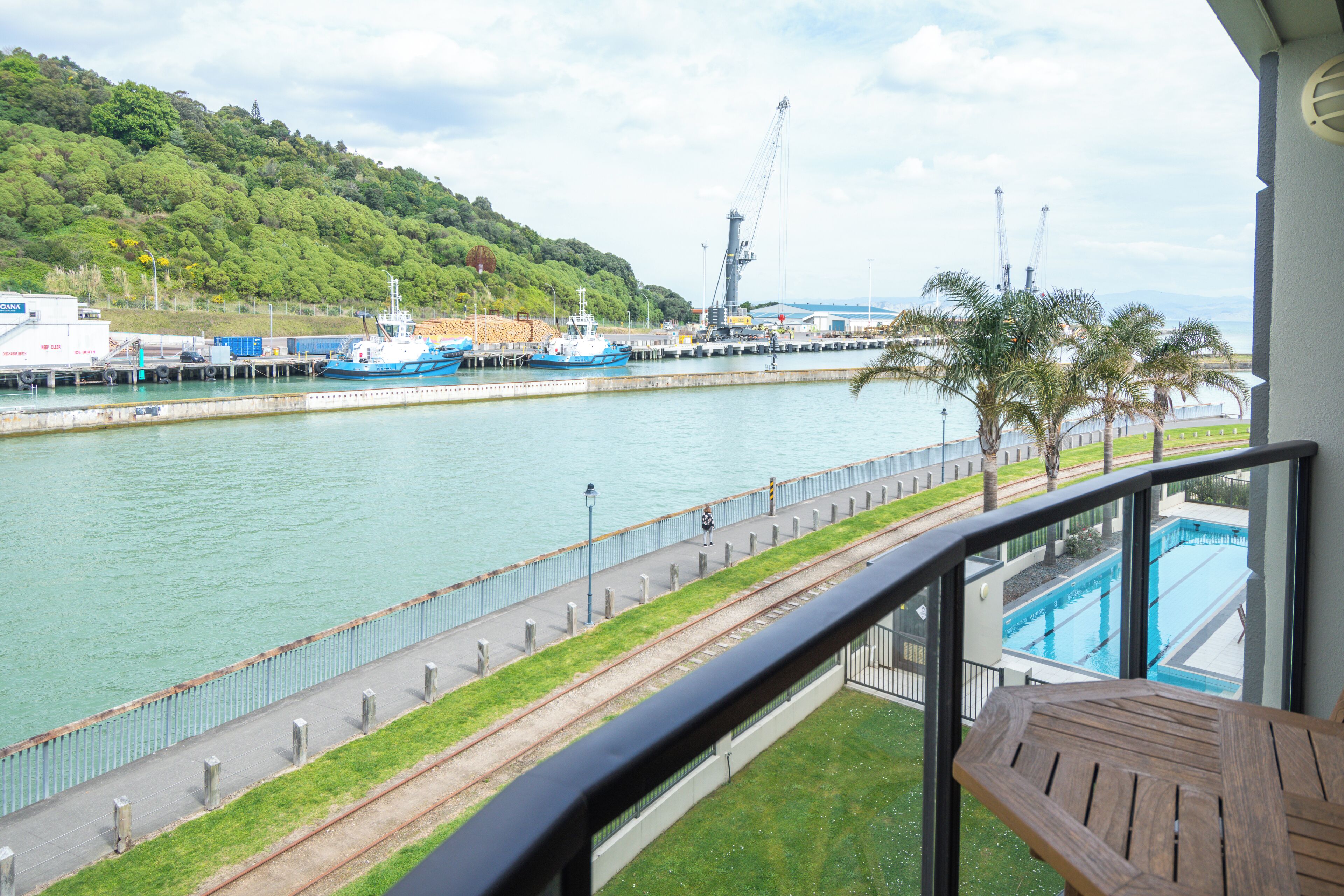 A balcony with a view of a harbor, including boats and a crane.