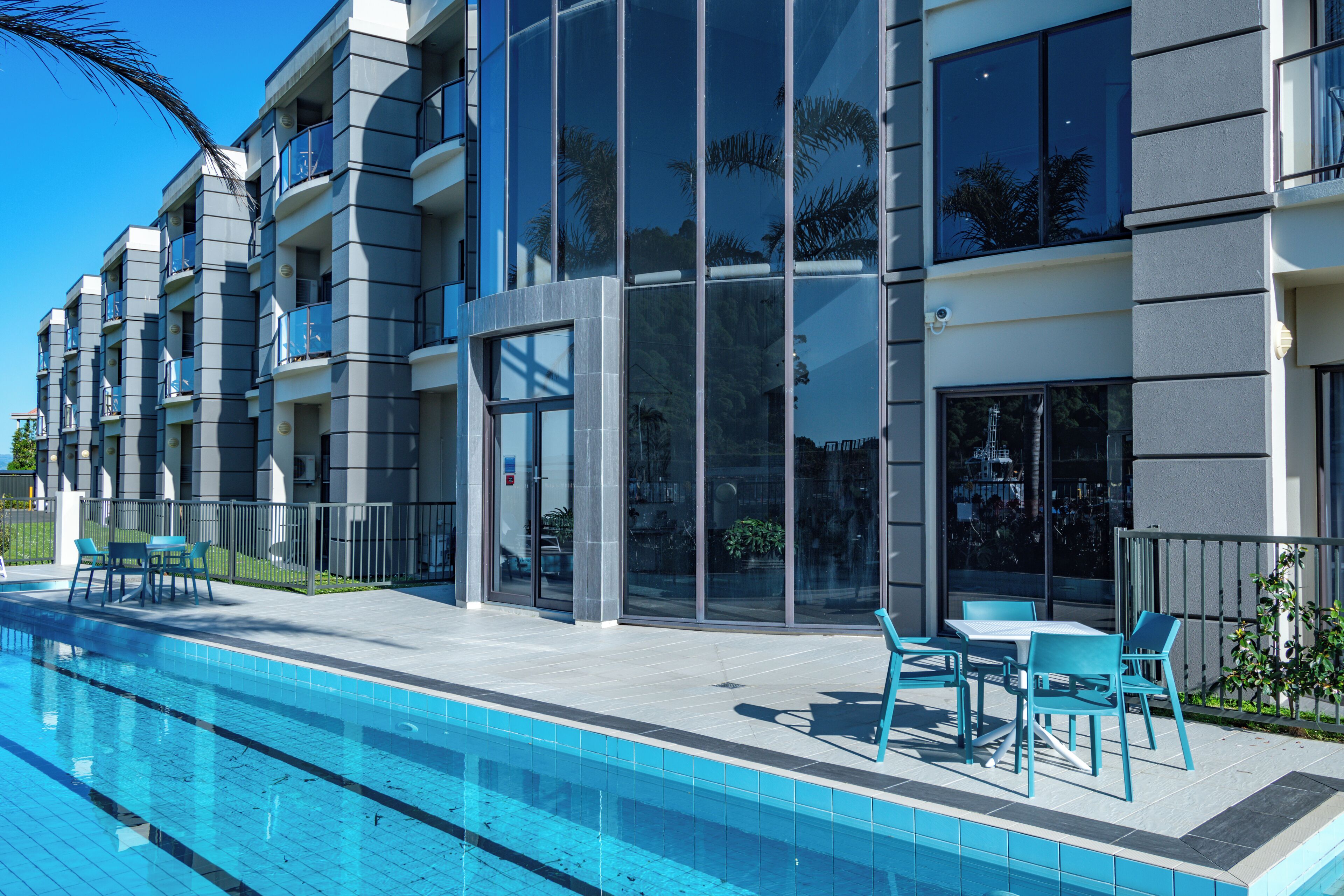 A modern building with a swimming pool, outdoor seating, and balconies.