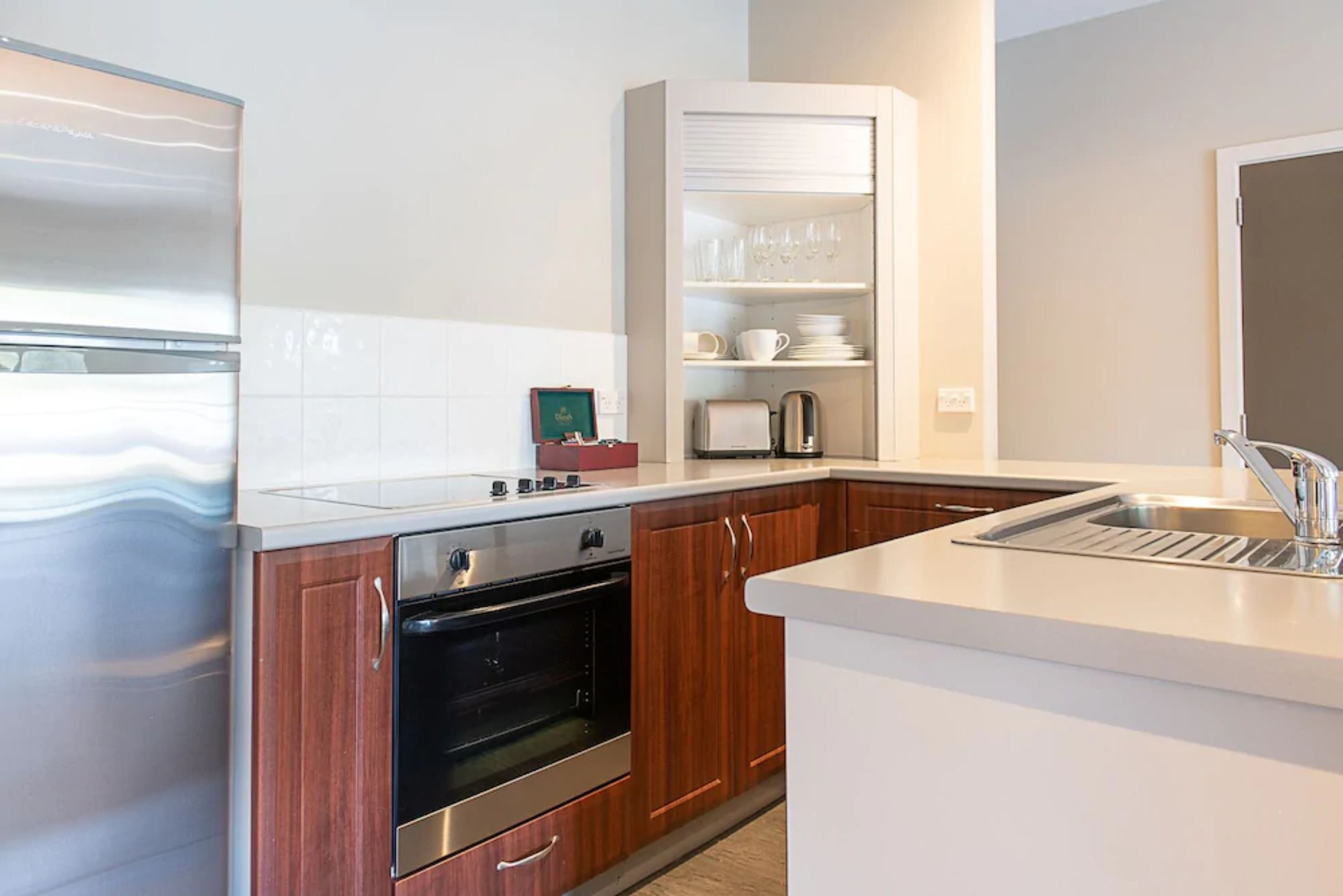 A modern kitchen with wooden cabinets, a built-in oven, a microwave, and a white countertop.