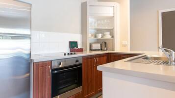 A modern kitchen with wooden cabinets, a built-in oven, a microwave, and a white countertop.