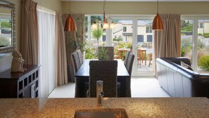 Una cocina con encimera de granito, un lavamanos y una zona de comedor con mesa y sillas.