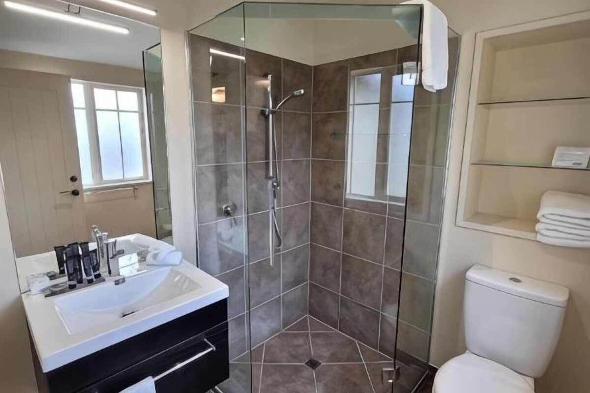 Un baño moderno con cabina de ducha de vidrio, un lavamanos blanco y un inodoro.