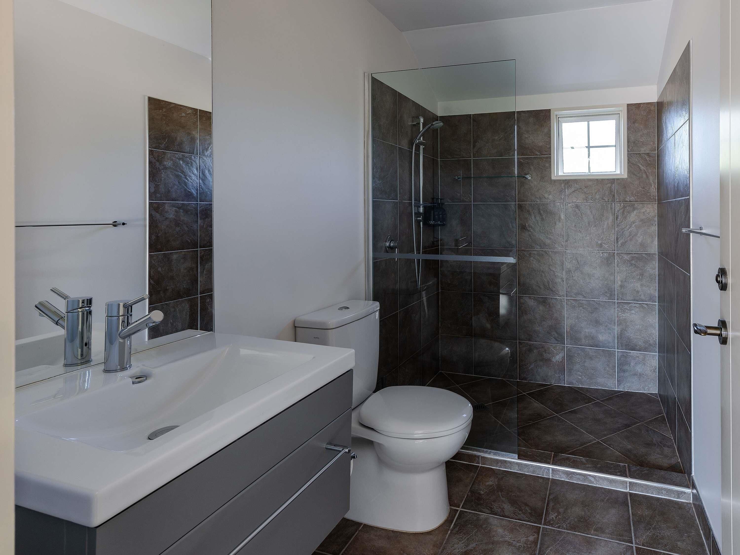 A modern bathroom with a shower, toilet, and sink.