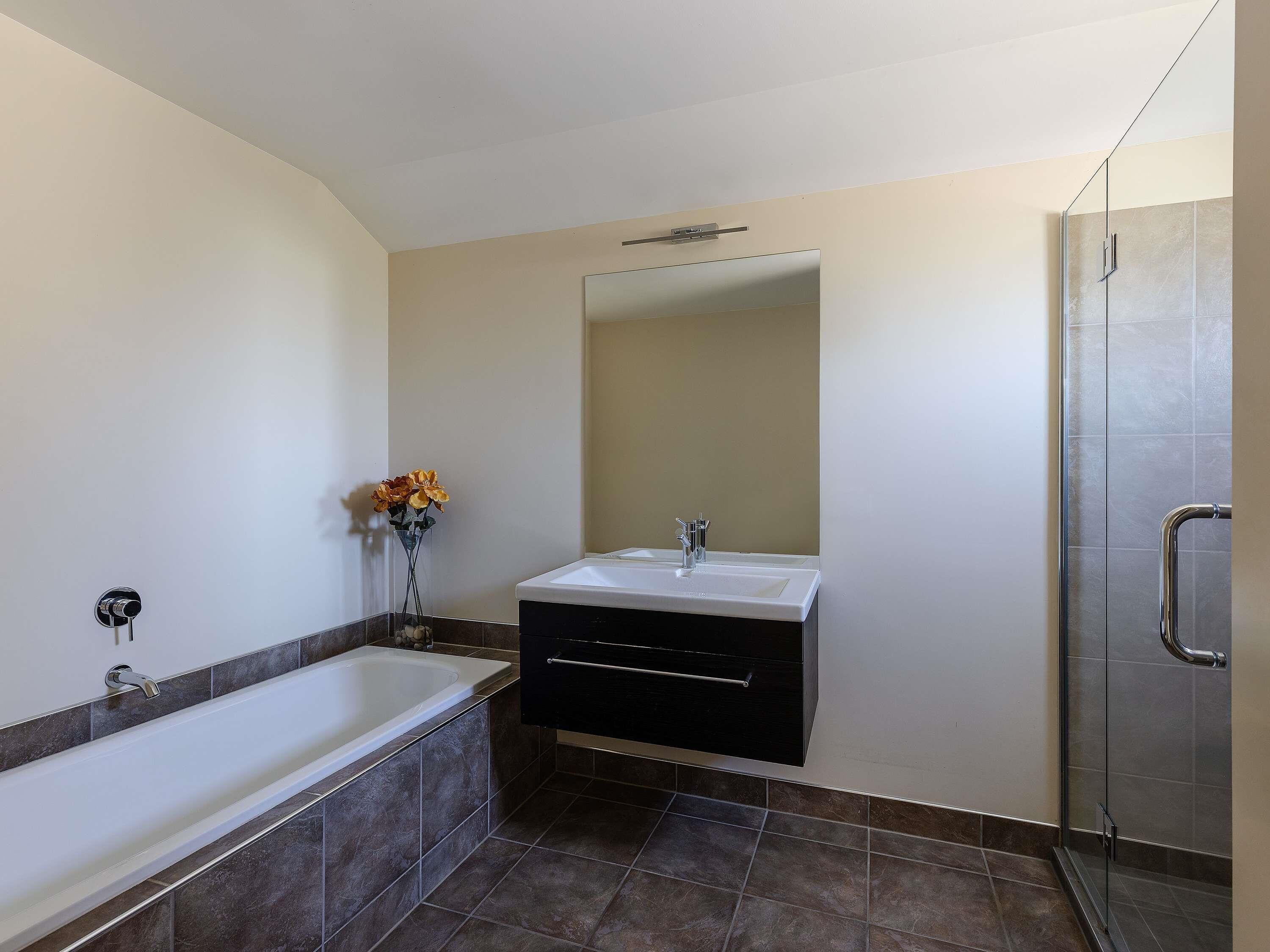 Un baño moderno con bañera, tocador con espejo y zona de ducha.