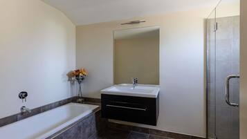 A modern bathroom with a bathtub, a vanity with a mirror, and a shower area.