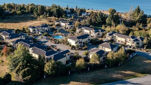 Zona residencial con casas, piscina y lago con montañas al fondo.