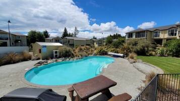 A swimming pool with a patio area, surrounded by residential buildings and greenery.