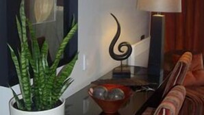 Uma sala de estar moderna com divisória de vidro, planta em vaso, luminária e sofá.