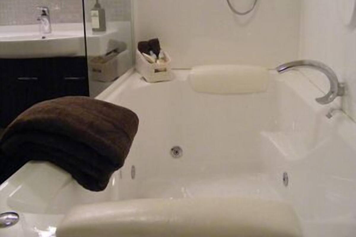 Een badkamer met een bad, een wastafel en een spiegel.