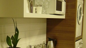 Uma cozinha compacta com pia, micro-ondas e máquina de lavar.