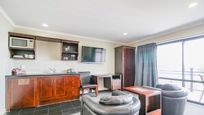 A modern living area with a kitchen, a flat-screen TV, a sofa, and a dining table. - Aotea Motor Lodge (Whanganui)