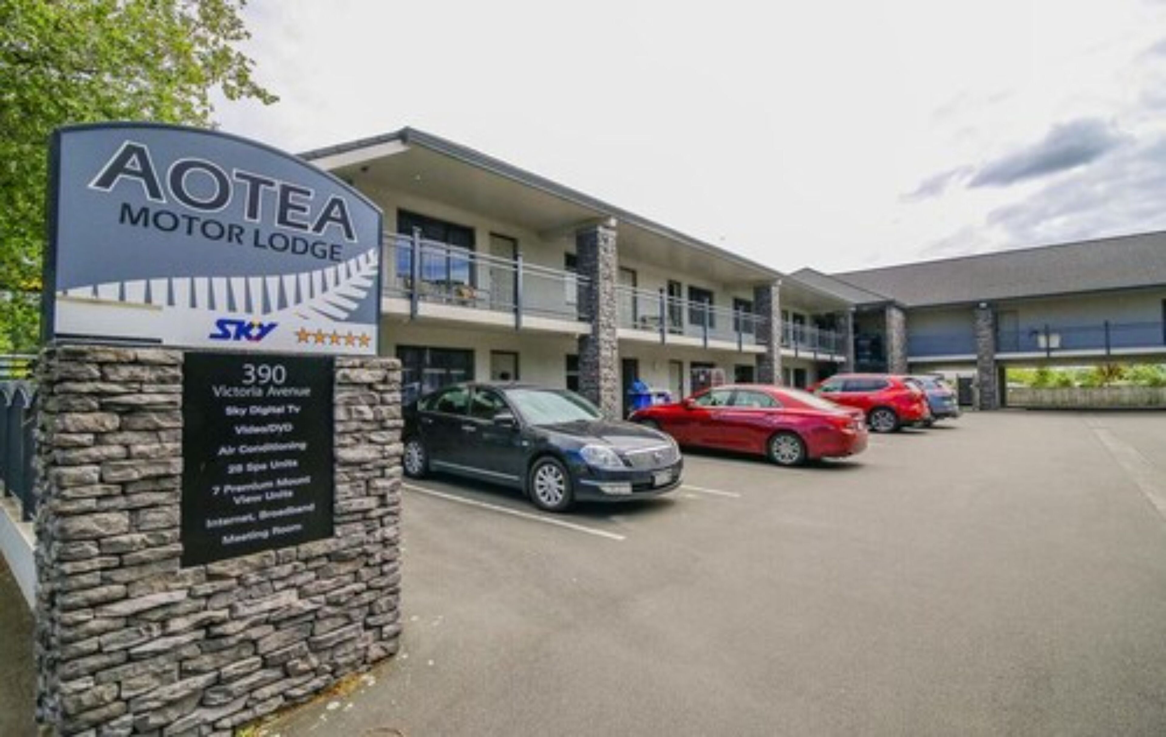 Un motel llamado AOTEA con un letrero que indica servicios como televisión Sky Digital, aire acondicionado, 29 espacios de estacionamiento, 7 suites premium e internet.