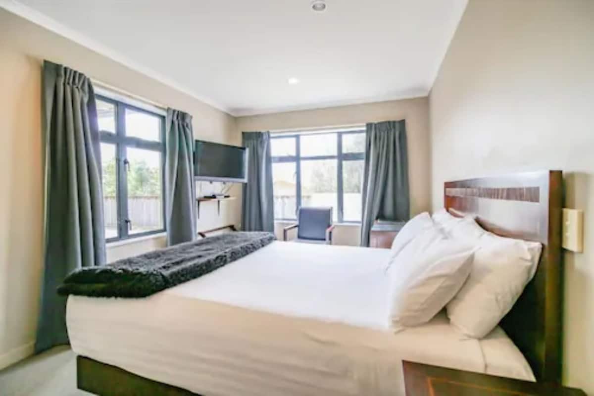 Una habitación de hotel con una cama grande, un escritorio y un televisor.