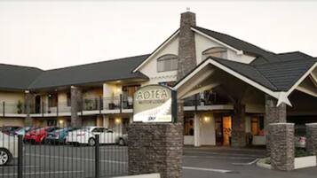 A motel with a signboard, multiple parking spaces, and a brick facade.