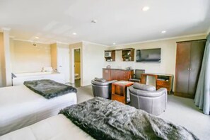 A hotel room with two beds, a kitchenette, a TV, and a wardrobe. - Aotea Motor Lodge (Whanganui)