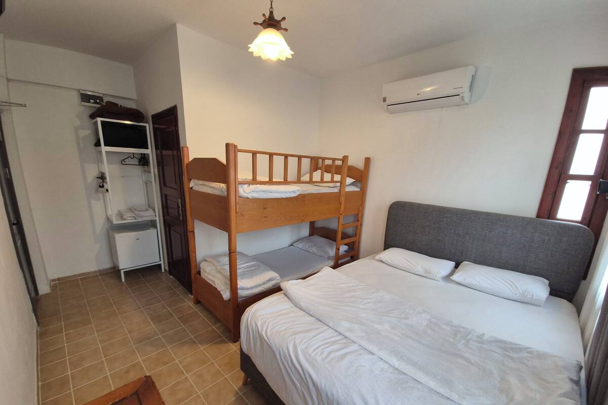 A bunk bed room with a desk and a wardrobe.