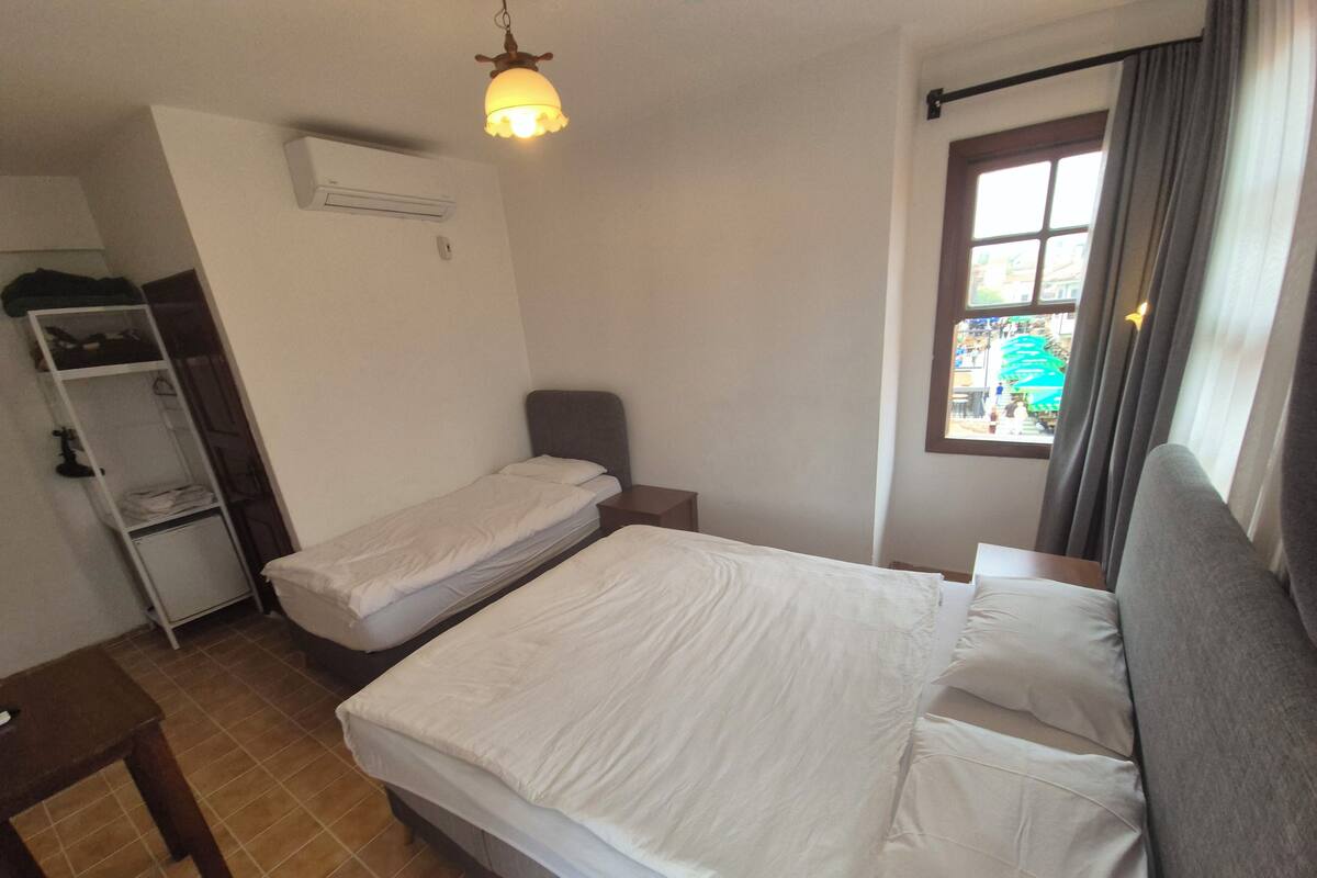 A bedroom with a bed, a bedside table, a wardrobe, and a window with curtains.