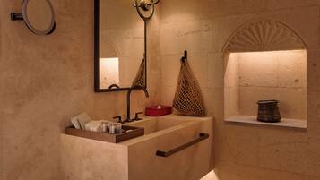 A modern bathroom with a large sink, a mirror, and a wall-mounted lamp.