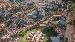 Un pueblo turco tradicional con casas de piedra, calles estrechas y un patio central con una mesa larga dispuesta para una comida.