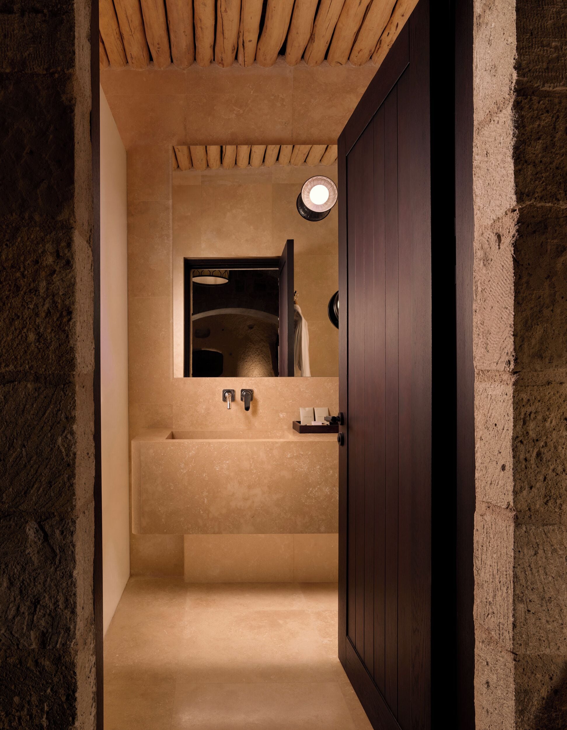Ein schmaler Flur führt zu einem Badezimmer mit Badewanne, Handtuchhalter und einer Leuchte.