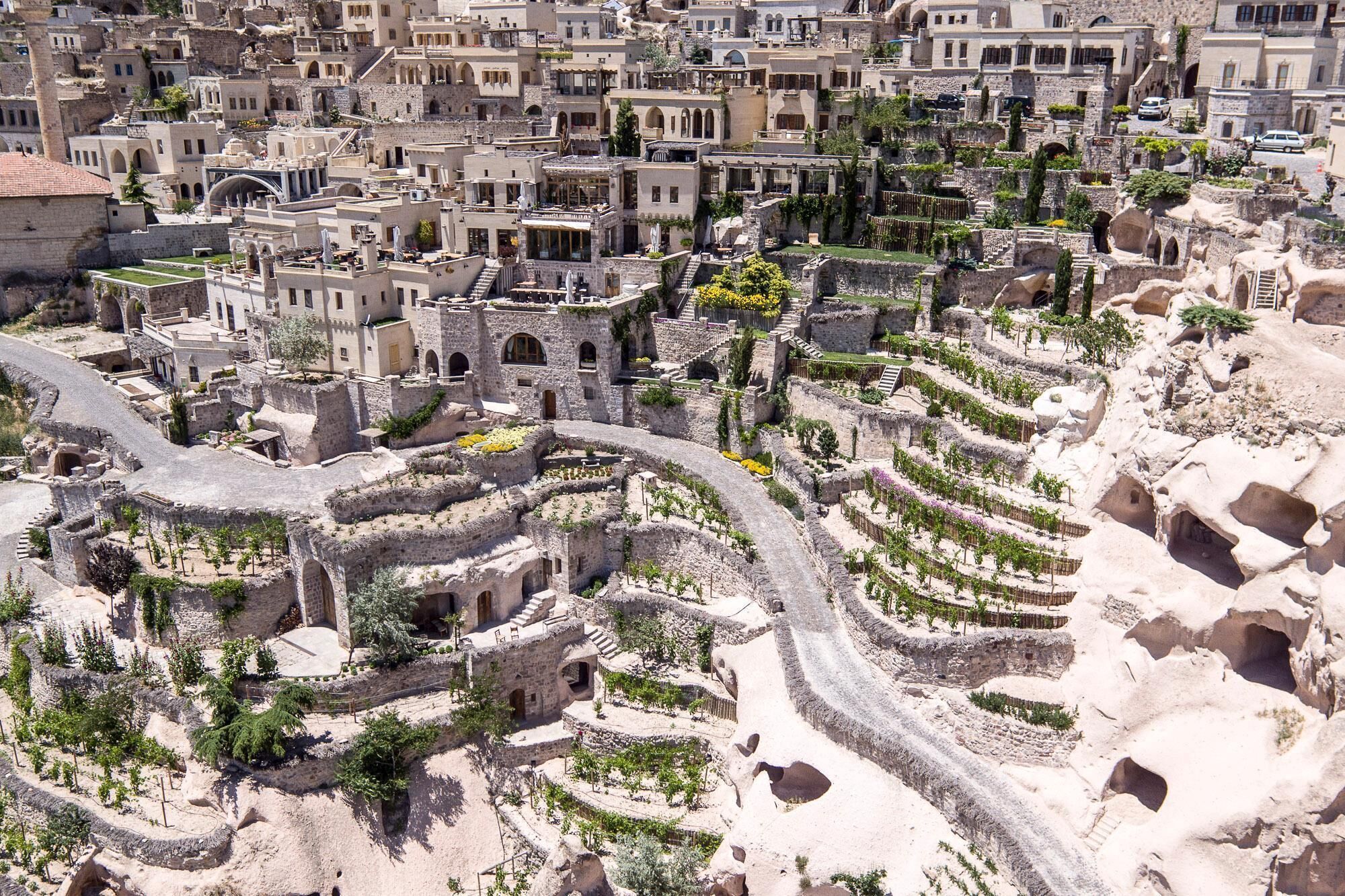 A historical cityscape with ancient stone buildings and terraced gardens.