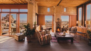Amplia sala de estar con chimenea, asientos cómodos y ventanas grandes que ofrecen vistas al paisaje desértico.