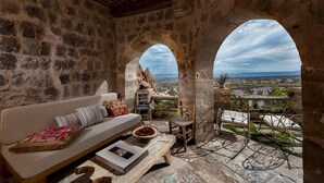 Una habitación con paredes de piedra, un sofá, una mesita y vistas a través de un arco.