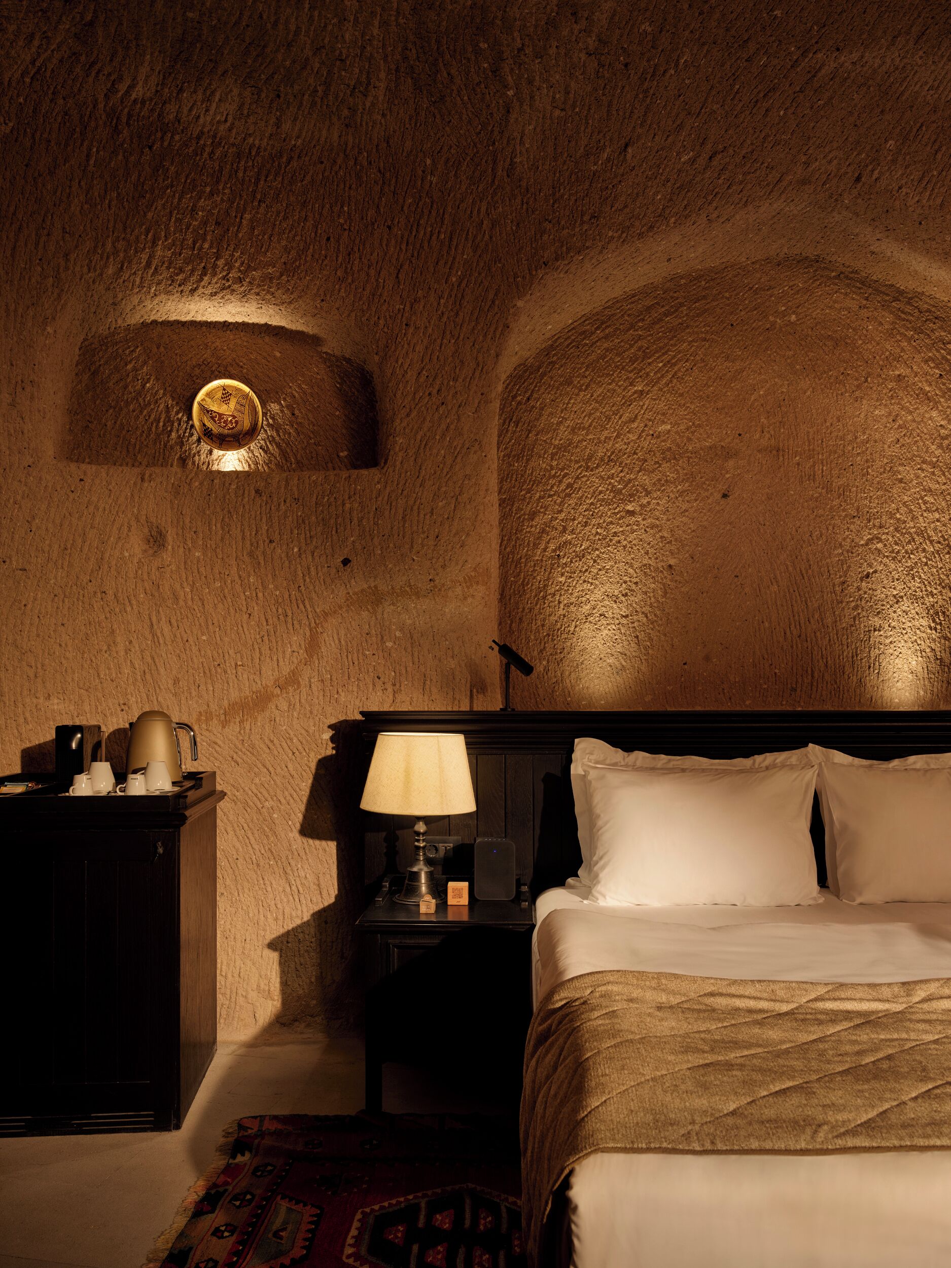 A cozy room with a bed, a nightstand, a lamp, and a small cabinet.