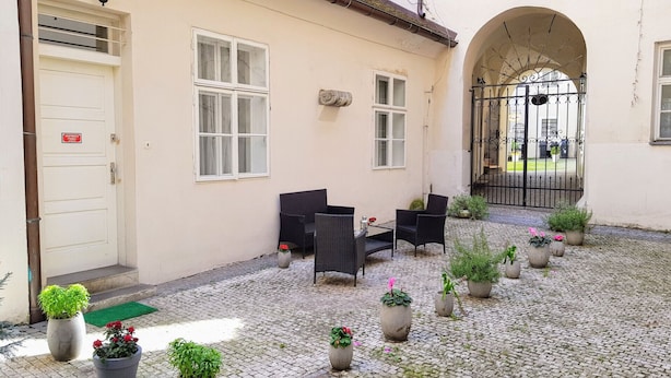 A courtyard with outdoor seating, potted plants, and a gated entrance.