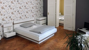 A bedroom with a bed, bedside tables, a wardrobe, and a hanging light fixture.