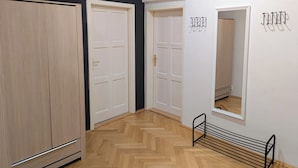 A room with a wooden wardrobe, two white doors, a mirror, and a metal rack.