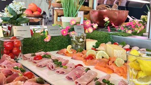 Una tabla de embutidos con diferentes carnes, quesos y guarniciones.