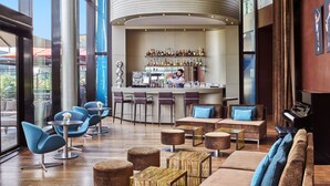 Zona de bar moderna con un cantinero, taburetes y una variedad de botellas de licor.