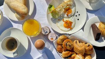 Une table de petit-déjeuner avec des croissants, des œufs, du jus et du café.