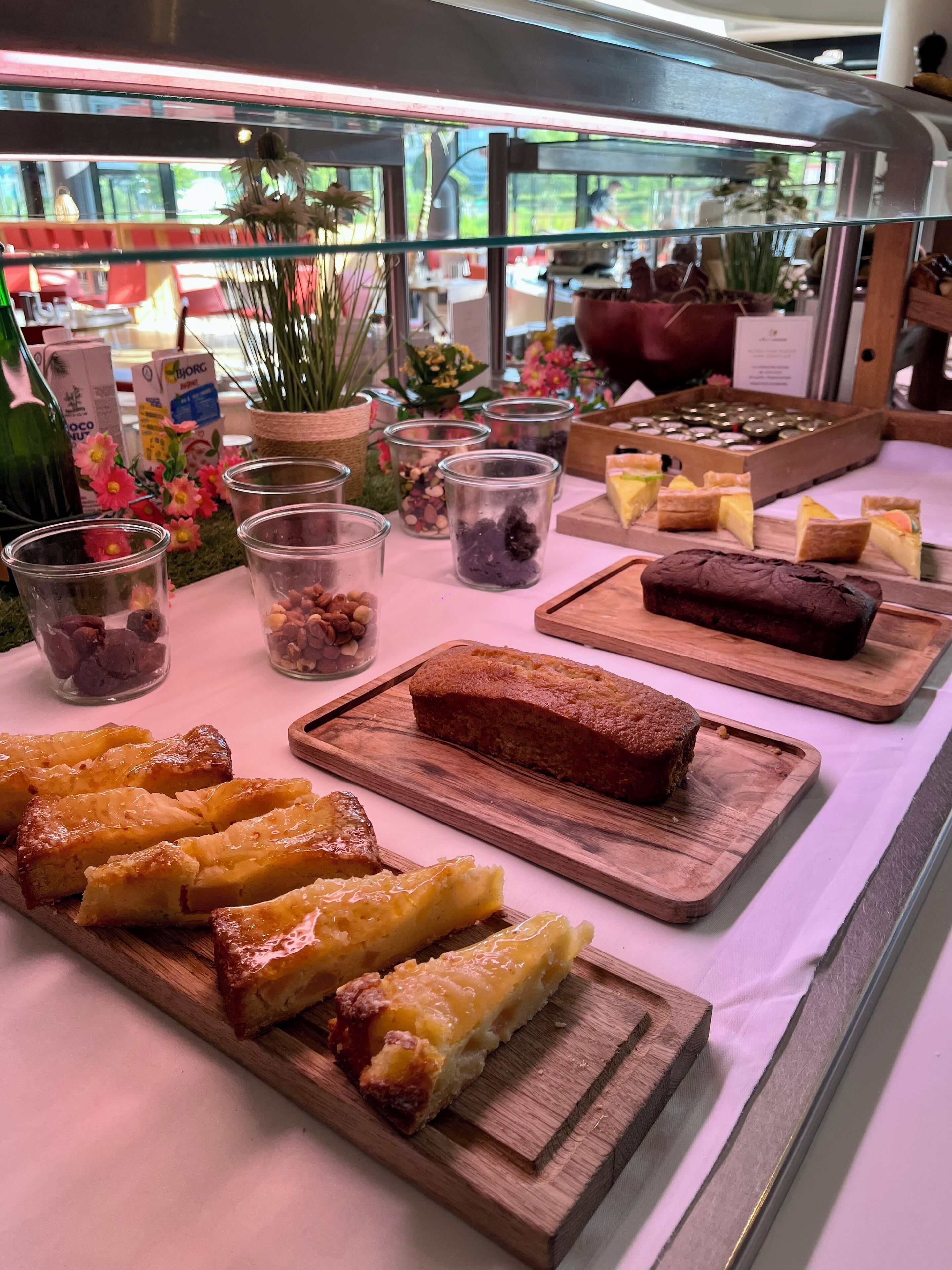 Una vitrina de pastelería con diversos productos horneados y botes de nueces y frutas secas.