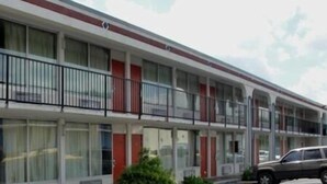 A motel with a row of rooms, each with a balcony and a small garden area. - Royal Inn Knoxville Airport Alcoa (Alcoa)