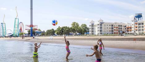 A beachside hotel with a water tower, amusement park rides, and a sandy beach.